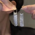 Nahaufnahme von silbernen Quastenohrringen mit glitzernden Strasssteinen und Rechteck-Design - Weiß K/Silber / Silber