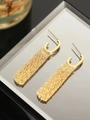 Detail goldener Quastenohrringe mit langen Metallketten, die auf einem Tablett reflektieren - 18K Gold / Gold