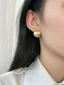 Detail of matte gold brushed semi-sphere earrings on model with elegant minimalist style - Gold