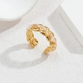 Gros plan d'une bague ouverte dorée à deux rangs avec perles roses sur surface en pierre - Corde à Perles Roses(R740-E-QK)