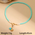 Detail of beaded ocean-style necklace with golden scallop shell and green fish charm - Scallop (M-N2236-beike)
