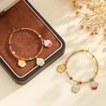 Détail de créoles dorées avec perles colorées et breloques cupcake en émail sur fond chaud - Coloré