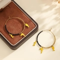 Détail de créoles dorées avec perles noires et pendentifs dauphins jaunes en émail - Noir