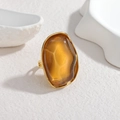 Artistic gold ring with an oversized irregular amber resin stone on a minimalist background - Light Coffee