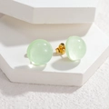 Sweet light green translucent sphere stud earrings with subtle shimmer on white stand - Green