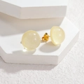 Macro shot of pale yellow resin ball stud earrings with shimmer glitter and gold posts - Beige