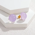 Gros plan de boucles d'oreilles en résine violette pailletée sur socles blancs - Violet