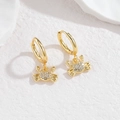 Goldene Krabben-Ohrringe mit glitzerndem Zirkonia auf einem weißen Steinhintergrund - Krabbe