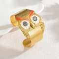 18k gold owl bangle featuring textured finish and colorful stone eyes on ceramic plate - Red