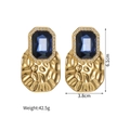 Detail view of gold earrings with large blue rectangular gems and textured metal - Dark Blue