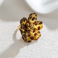 Elegante anillo floral de oro 18k con pétalos de carey sobre superficie blanca con textura - Flor de Seis Pétalos Redondos
