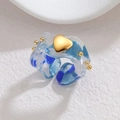 Blauer Harzring mit goldenem Herz und Tintenstruktur auf weißem Hintergrund mit Textur - Blau