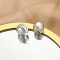 Polished silver bean earrings on mirror tray with elegant satin fabric background - Silver