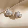 Macro di orecchini a cuore in argento con zirconi bianchi su sfondo di seta color champagne - Argento