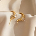 Detalle de aros dorados con circonitas sobre un fondo de tela de seda color champán - Dorado