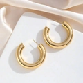 Detailed view of polished 18K gold-plated C-shaped chunky earrings on white silk - Gold