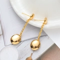 Elegante goldene Hängeohrringe mit polierten Ovalanhängern auf einer Porzellanschale - Gold