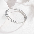 Detailopname van drie minimalistische zilveren roestvrijstalen armbanden op een wit dienblad - Zilveren Minimalistisch Glad (CXB1251-01)