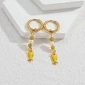 Detail of gold hoop earring with green beads and yellow fish drop charm on white stone - Yellow Fish Style