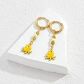 Golden hoop earrings with yellow octopus charm and green beads on a stone display - Yellow Octopus Style