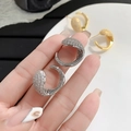 Close-up of pavé zircon C-shaped hoop earrings in gold and silver luxury finish - 24K / Silver