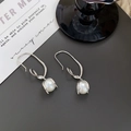 Makroaufnahme von silbernen Knotenohrringen mit Perlen auf grauer Oberfläche - Silber (A0624A)
