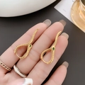 Macro shot of gold snake hoop earrings with green gemstone eyes and scaly texture - Gold (A0632A)