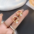 Gedetailleerde macro-opname van gouden oorringen met elegante witte parels en gladde afwerking - Goud (A0605A)