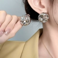 Primer plano de una modelo con pendientes de esfera plateada y diseño cóncavo texturizado - Grande (A0216B) / Plateado