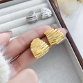 Primer plano detallado de pendientes dorados semicirculares con textura de ondas - Dorado