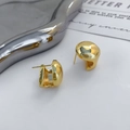 Makro-Detail von hochglanzpolierten vergoldeten geometrischen Ohrringen auf Silber - Gold (A0730A)