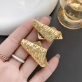 Gold plated irregular wrinkled earrings with a unique textured layered design worn on ear - Gold