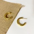 Close-up of golden hollow tube C-shaped hoop earrings with polished mirror finish surface - Medium Style / Gold