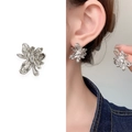 Pendientes de flor plateada con circonita y vista del producto puesto en oreja - Plateado