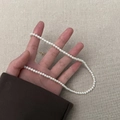 Close-up of elegant pearl necklace with gold clasp held against a textured background - 4mm Pearl Necklace (A0265A-1) / White