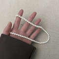 Detail of white round pearl necklace with gold clasp held by hand on textured background - 6mm Pearl Necklace (A0265A-2) / White