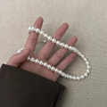 Macro detail of round cream pearls with golden metal extension chain on beige fabric - 8mm Pearl Necklace (A0265A-3) / White