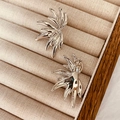 Detailed view of silver angel wing stud earrings on a beige velvet jewelry display - Silver