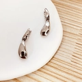 Dettaglio macro di orecchini a goccia d'argento lucido su vassoio di ceramica - Rame Placcato Oro / Argento (A0132A)