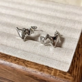 Close-up of polished silver geometric wave stud earrings on beige jewelry display tray - Glossy / Silver
