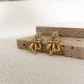Nahaufnahme goldener Zirkon Blumen und Schleifen Ohrstecker auf texturierter Steinfläche - Gold (A0339B)