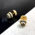 Macro detail of gold-plated spherical stud earrings with black and white pavé cubic zirconia - Gold