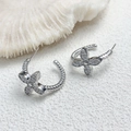 Detail von silbernen gedrehten Creolen mit funkelndem Schmetterling-Zirkon-Vierblatt-Kleeblatt - Silber