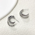 Detail van zilveren C-vormige oorbellen met gedraaide metalen textuur op witte basis - A0641c Zilver