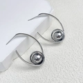 Detailaufnahme eines polierten silbernen Kugelohrrings auf einem weißen Steinsockel - Spiralball-Stil (A0420B) / Silber