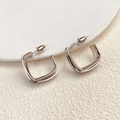 Primer plano macro de pendientes cuadrados geométricos plateados pulidos sobre cerámica - Plata (A0320C)