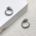 Detail of silver snake-themed hoop earrings with green zircon eyes on a minimalist stone base - Silver(A0277B)