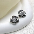 Macro shot of silver camellia earrings with 5A zircon inlay on white display - Silver
