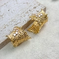 Detailansicht gewebter Goldstecker mit glitzernden Kristallen auf einer Steinunterlage - Gold