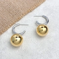 Detail view of high-polished 18k gold ball pendant earrings on C-shaped silver hooks - Gold and Silver Contrast